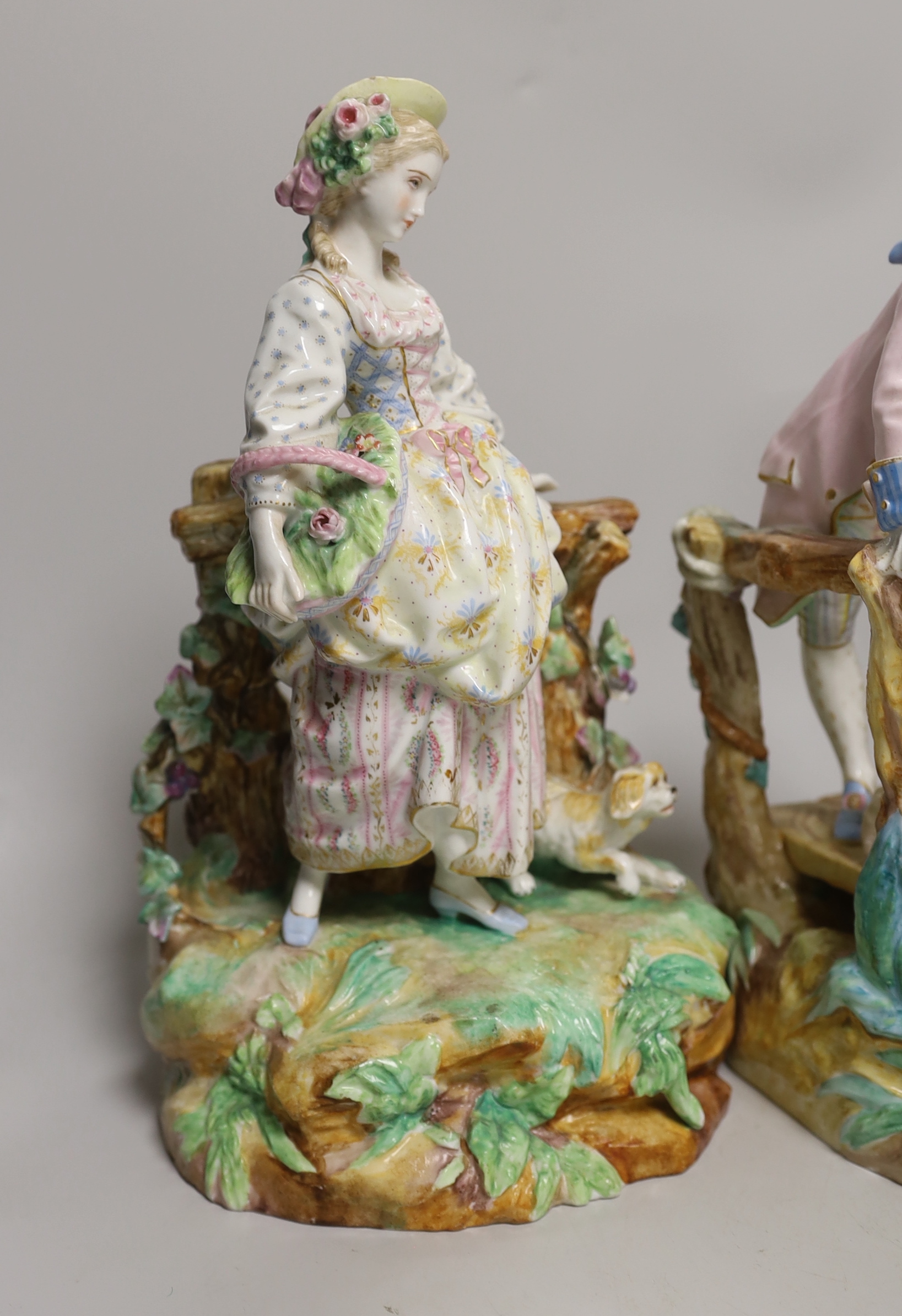 Three German porcelain figures including a Sitzendorf group of a young couple and a sheep, together with a pair of lovers with dogs, highest 28cm